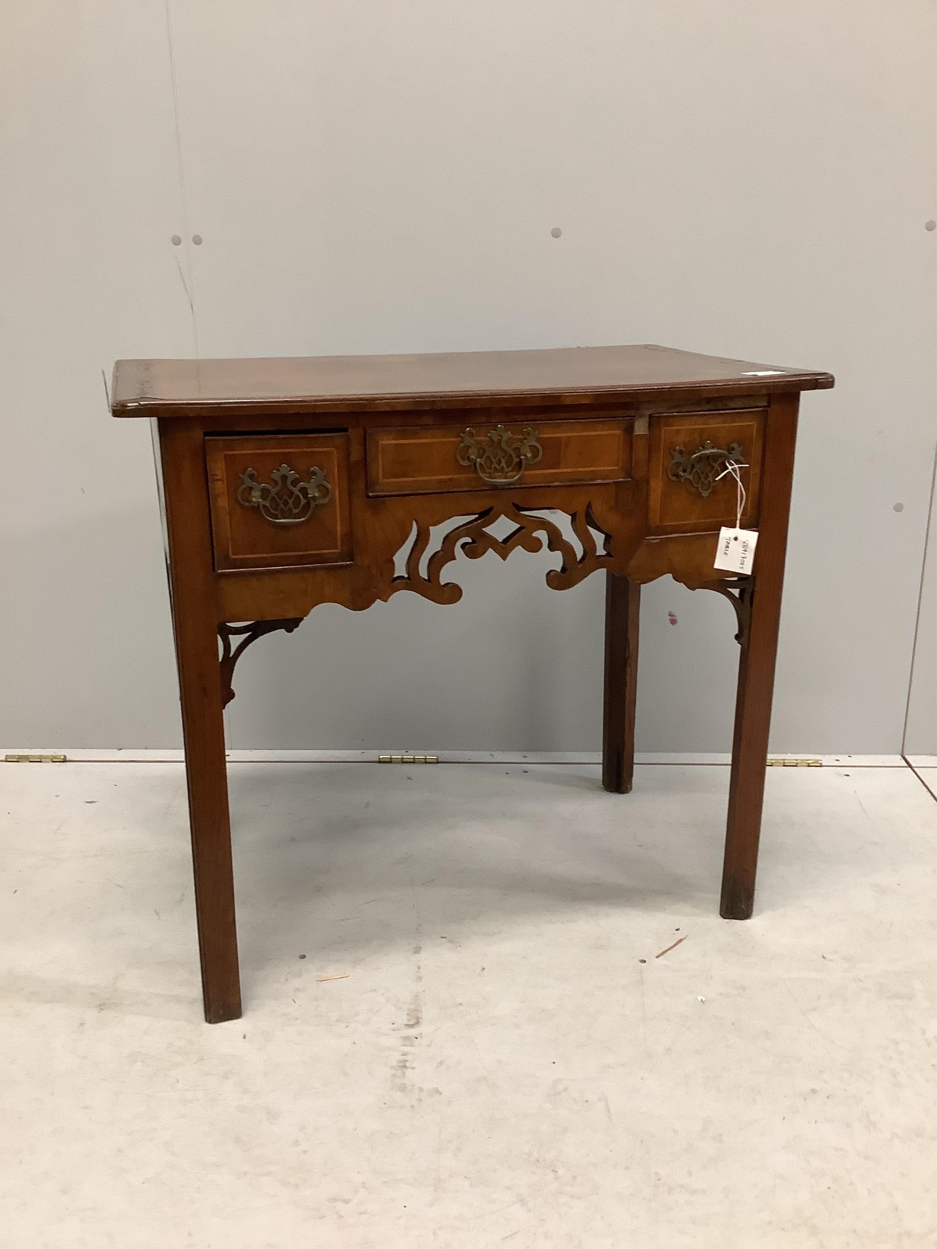 A mid 18th century walnut lowboy quarter veneered with a rectangular top above three drawers and a pierced apron on chamfered legs, width 80cm, depth 49cm, height 73cm. Condition - poor to fair